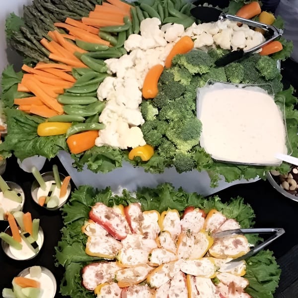 A vibrant vegetable platter with carrots, broccoli, cauliflower, snap peas, and mini bell peppers.