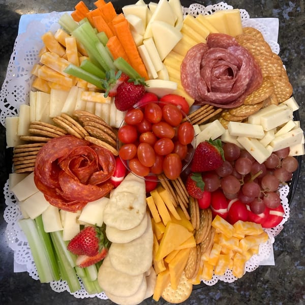 Overhead view of a charcuterie board with cheeses, meats, crackers, vegetables, and fruits.